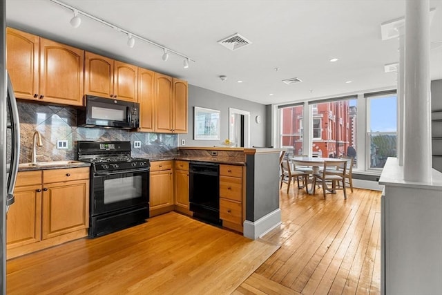 99 Washington St Unit 23, Salem, MA 01970 - kitchen with black appliances, backsplash, light wood finished floors, a peninsula, and a sink