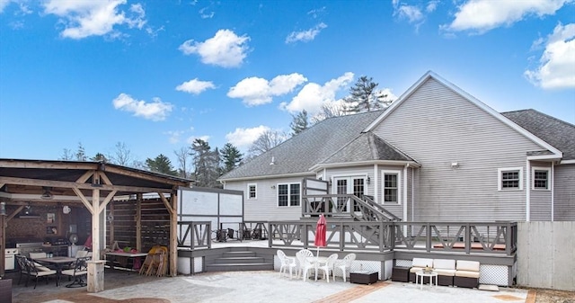 back of property featuring a deck, a patio, a gazebo, a shingled roof, and outdoor dining space