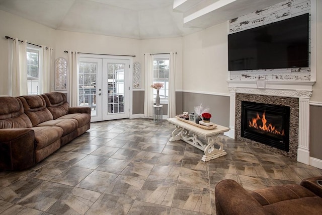 living area with healthy amount of natural light, french doors, a tiled fireplace, and baseboards