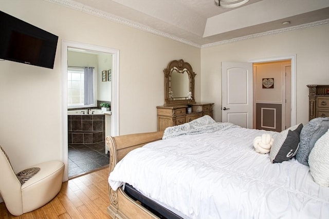 bedroom featuring light wood-style flooring, crown molding, and a tray ceiling