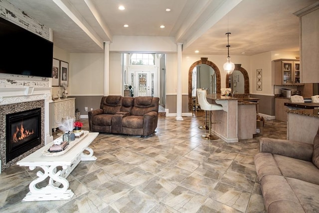 living room with baseboards, a glass covered fireplace, recessed lighting, and arched walkways