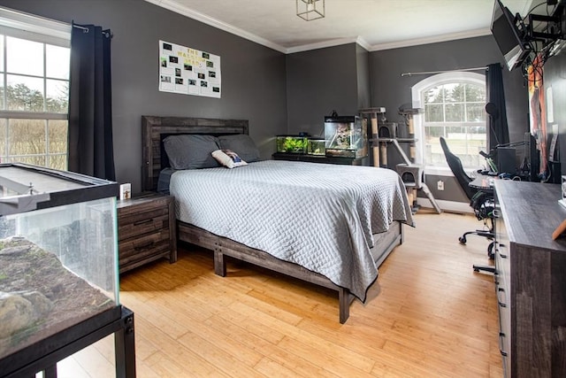 bedroom with light wood-type flooring, crown molding, and baseboards