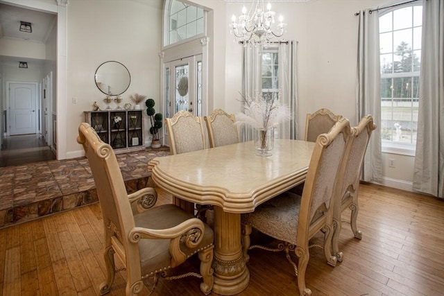 dining room with a chandelier, hardwood / wood-style flooring, baseboards, and ornamental molding