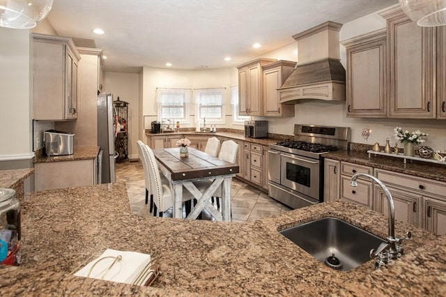kitchen with appliances with stainless steel finishes, a sink, premium range hood, stone counters, and recessed lighting