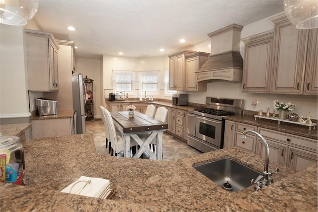 kitchen with appliances with stainless steel finishes, a sink, custom range hood, stone countertops, and recessed lighting