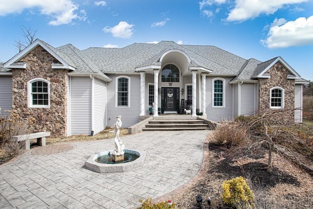 ranch-style home with stone siding and roof with shingles