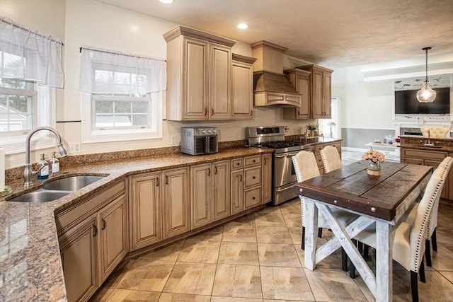 kitchen featuring gas range, a sink, custom range hood, stone counters, and recessed lighting
