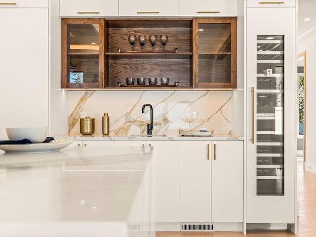 bar with sink, white cabinetry, and decorative backsplash