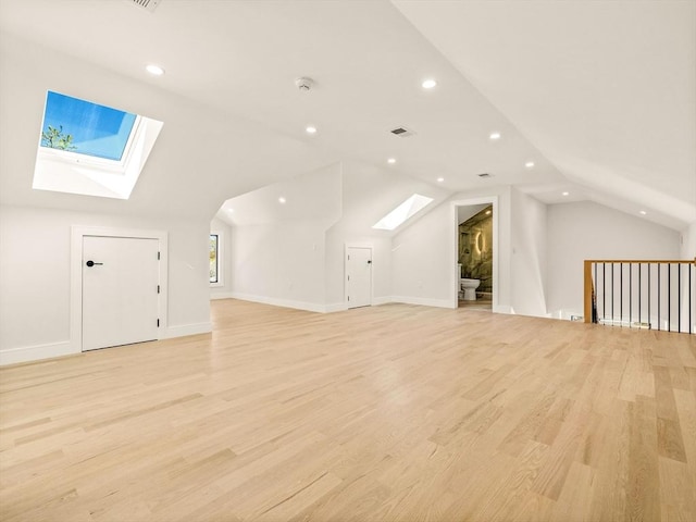 bonus room featuring vaulted ceiling with skylight and light hardwood / wood-style flooring