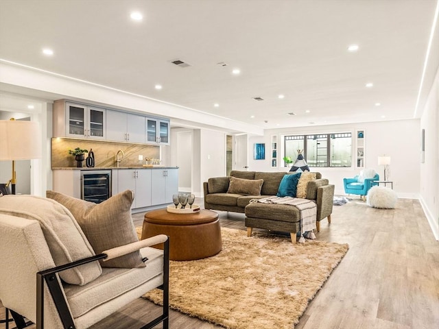 living room with indoor wet bar, light wood-type flooring, and wine cooler