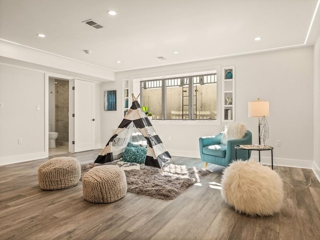 sitting room with wood-type flooring and built in features