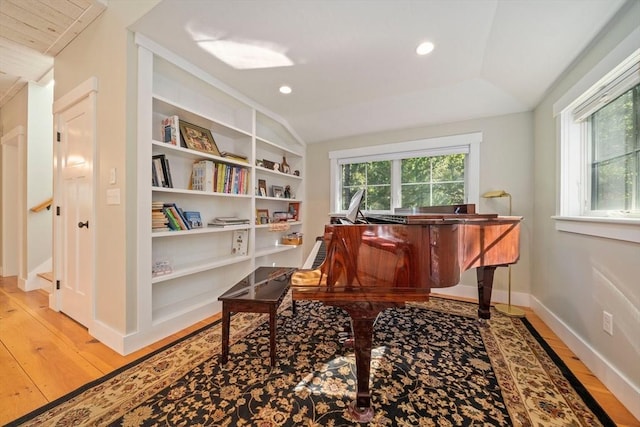 miscellaneous room with built in shelves, lofted ceiling, and light hardwood / wood-style flooring