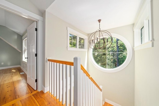 hallway featuring vaulted ceiling, light hardwood / wood-style flooring, and an inviting chandelier