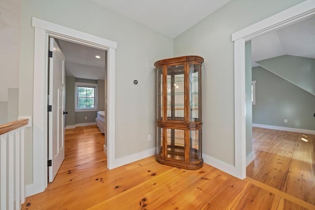 hall with vaulted ceiling and light hardwood / wood-style flooring