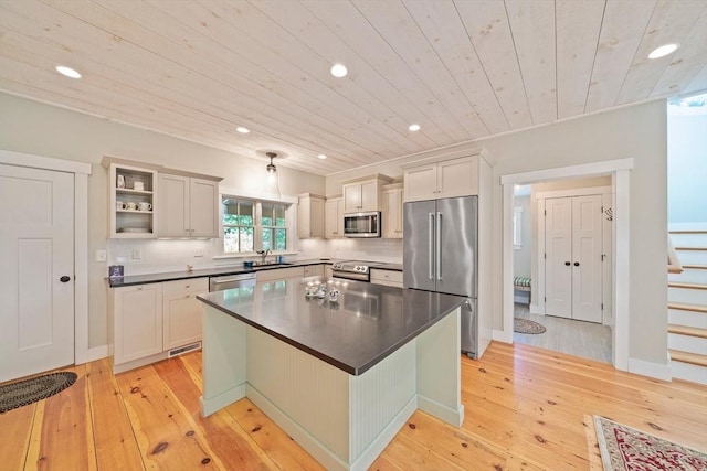 kitchen featuring sink, a kitchen island, appliances with stainless steel finishes, light hardwood / wood-style floors, and wood ceiling