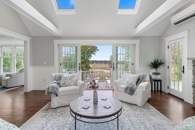 living room with dark wood-type flooring, plenty of natural light, a wall mounted AC, and vaulted ceiling with skylight