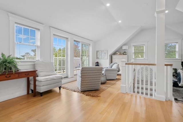 living room featuring light hardwood / wood-style flooring, decorative columns, lofted ceiling, and a wealth of natural light