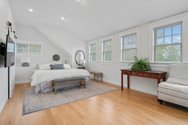 bedroom featuring lofted ceiling, light wood-type flooring, a barn door, and multiple windows