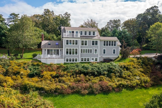 back of house with a balcony and a lawn