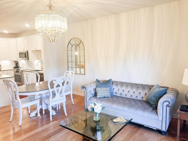 living area with baseboards, light wood-style flooring, and an inviting chandelier