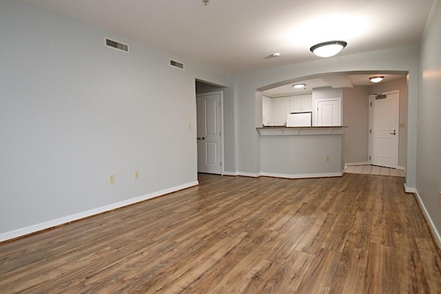 unfurnished living room with visible vents, baseboards, and wood finished floors