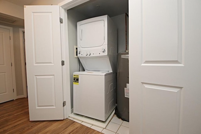 clothes washing area featuring visible vents, laundry area, water heater, light wood-style floors, and stacked washer / drying machine