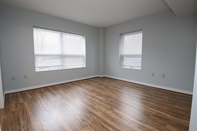 spare room featuring baseboards and wood finished floors