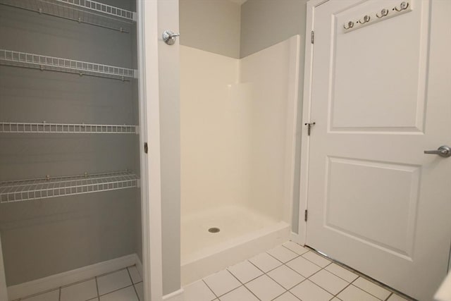 bathroom featuring tile patterned floors, baseboards, and a stall shower