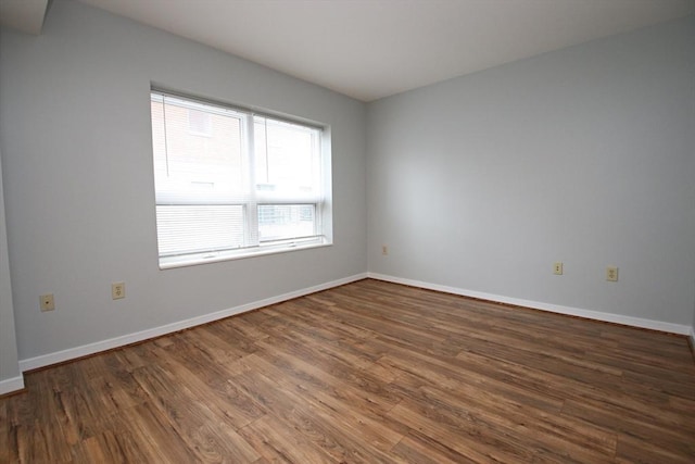 spare room featuring baseboards and wood finished floors