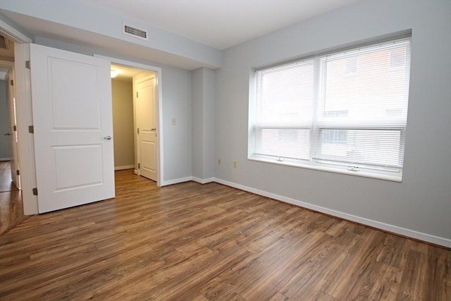 spare room featuring wood finished floors, visible vents, and baseboards