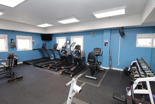 workout area featuring baseboards and a textured ceiling