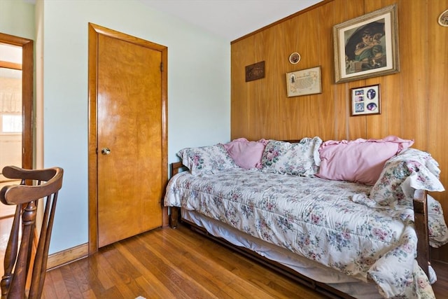 bedroom featuring dark wood-type flooring and wooden walls