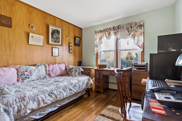 bedroom with dark hardwood / wood-style flooring, wooden walls, and a baseboard radiator