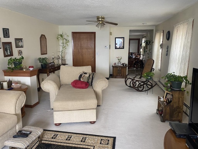 living area featuring ceiling fan, baseboard heating, a textured ceiling, and light colored carpet