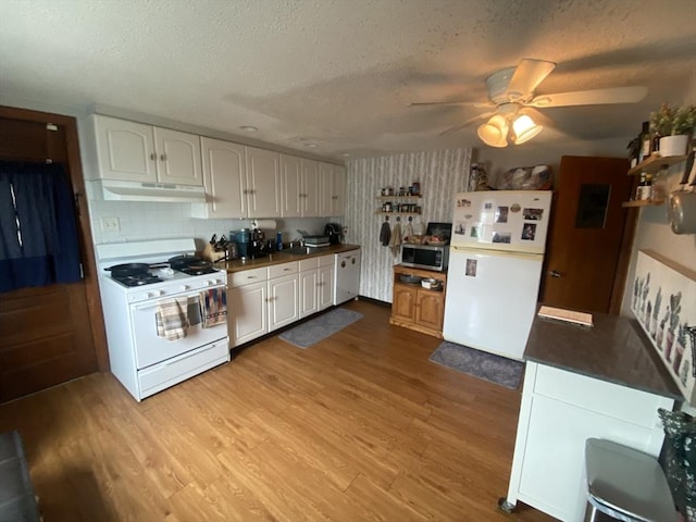 kitchen featuring dark countertops, white appliances, under cabinet range hood, and wood finished floors