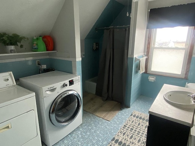 clothes washing area with washer and dryer, laundry area, a sink, and light tile patterned floors