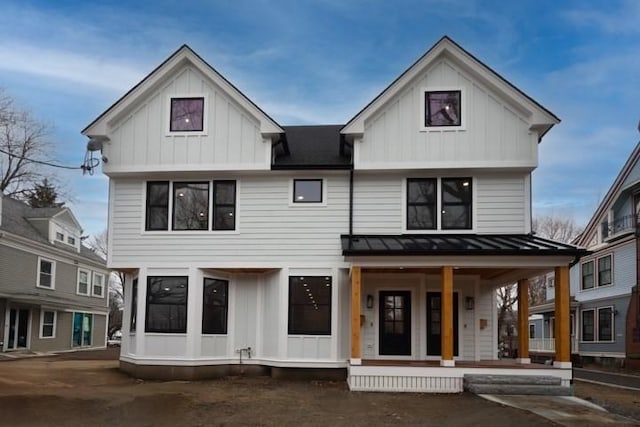 modern farmhouse style home featuring board and batten siding, a standing seam roof, a porch, and metal roof