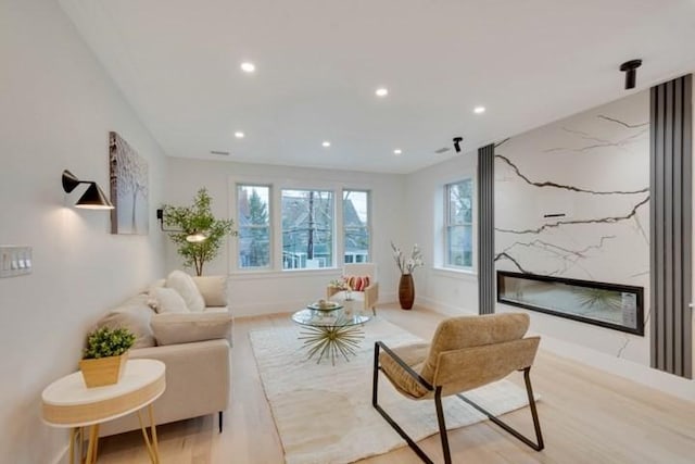 living area with recessed lighting, light wood-style flooring, baseboards, and a premium fireplace