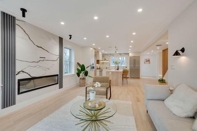 living room featuring a large fireplace, a wealth of natural light, light wood-style flooring, and recessed lighting