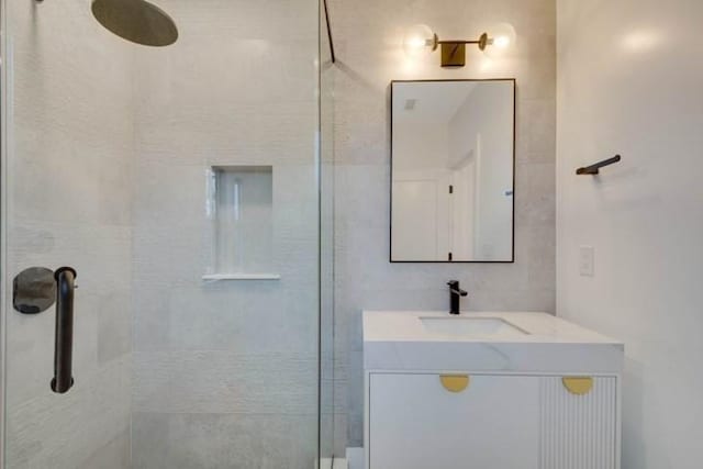 full bathroom with a tile shower and vanity