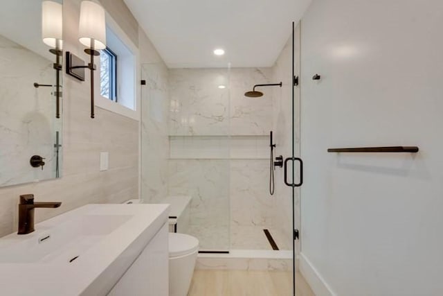 bathroom with a marble finish shower, toilet, vanity, tile walls, and recessed lighting