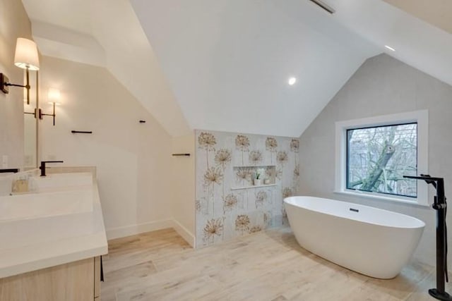 full bathroom featuring lofted ceiling, a sink, wood finished floors, a soaking tub, and double vanity