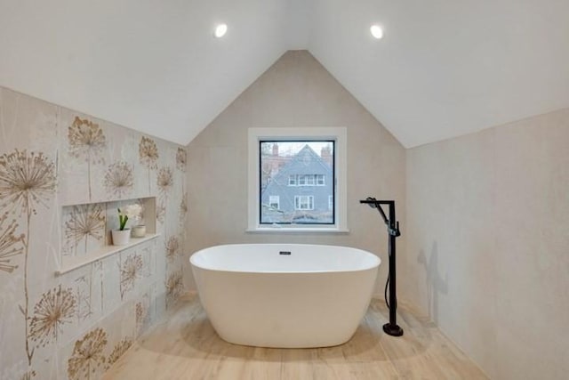 full bathroom with a freestanding tub and vaulted ceiling