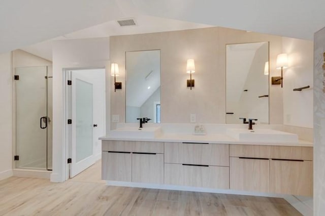 full bath featuring a stall shower, vaulted ceiling, a sink, and wood finished floors