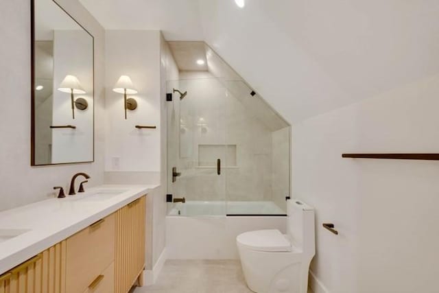 bathroom featuring double vanity, toilet, shower / bath combination with glass door, vaulted ceiling, and a sink