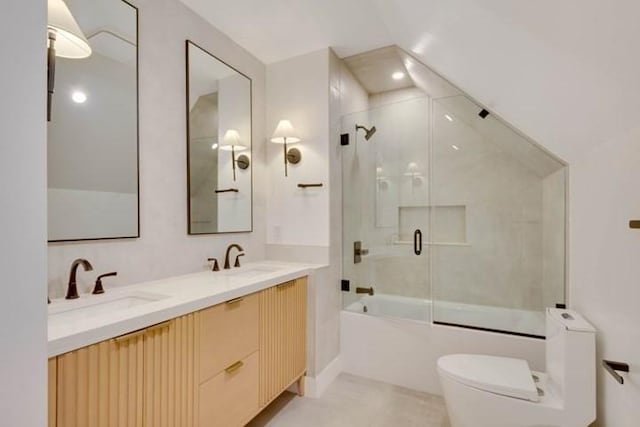 full bathroom featuring toilet, double vanity, bath / shower combo with glass door, and a sink