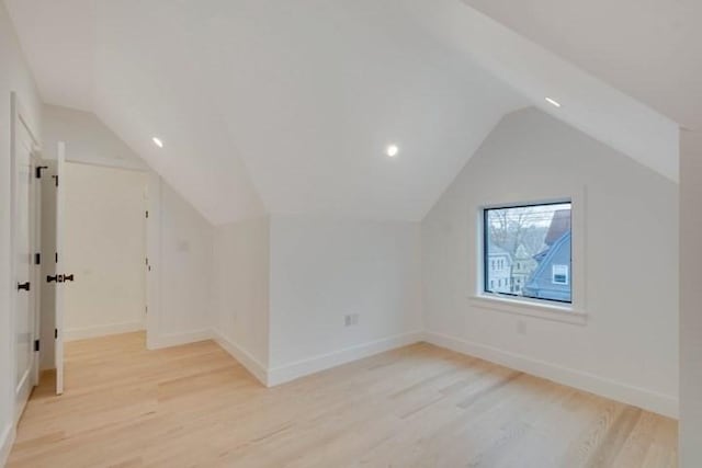 additional living space with baseboards, vaulted ceiling, and light wood finished floors