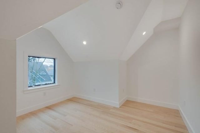 additional living space featuring lofted ceiling, baseboards, and light wood finished floors