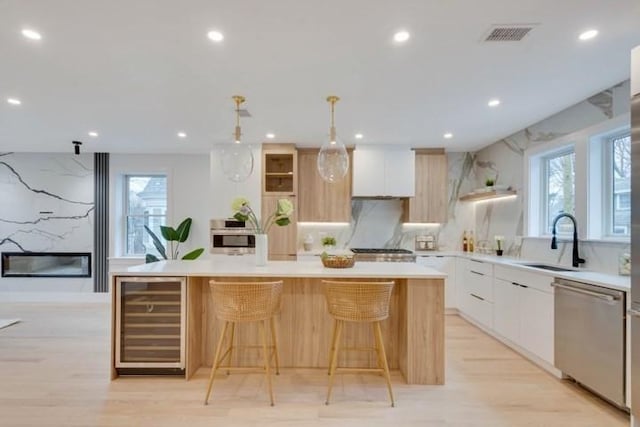 kitchen featuring beverage cooler, modern cabinets, a kitchen island, stainless steel dishwasher, and a sink