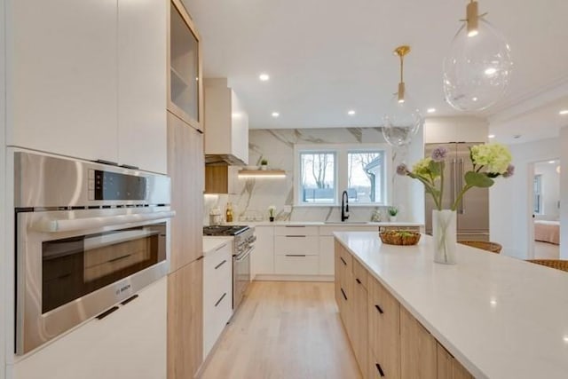 kitchen featuring modern cabinets, appliances with stainless steel finishes, light countertops, and a sink